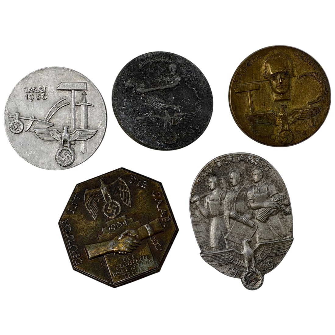 Third Reich Nazi Set of Tinnie Badges: A set of pin-back commemorative badges (tinnies) from the Third Reich period, including examples marked '1 Mai 1936', 'Tag der Arbeit 1935', 'Tag der Arbeit 1934', a 'Deutsch ist die Saar' 1934