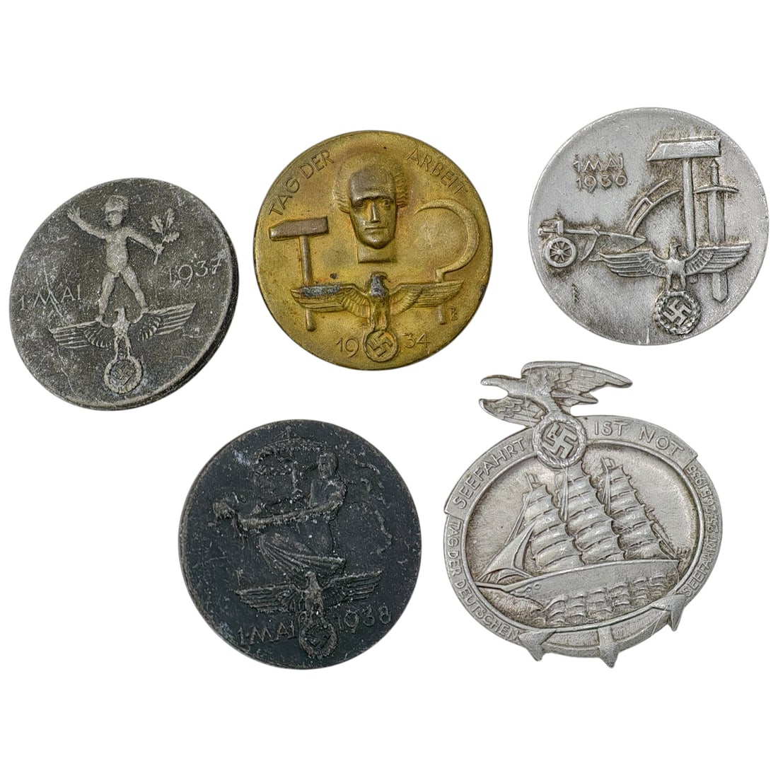 Nazi Third Reich Tinnie Event Badges: A set of Third Reich commemorative pin badges (tinnies), including round '1 Mai' / 'Tag der Arbeit' May Day badges dated 1934, 1936, 1937, and 1938, plus one 'Seefahrt ist Not' maritime badge marked