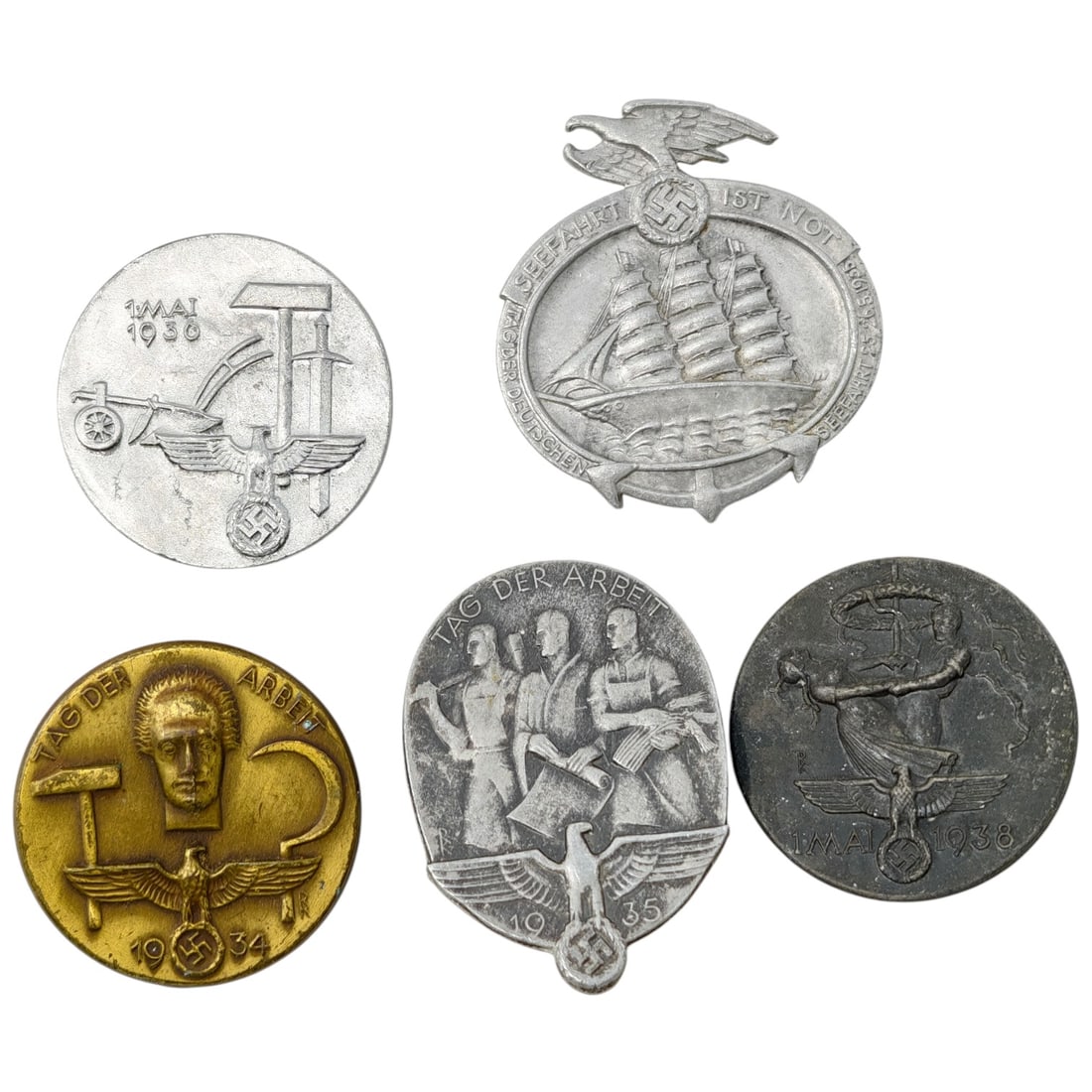 Third Reich Nazi Set of Tinnie Badges: A lot of pressed-metal tinnie badges from the Third Reich period, including a set of 'Tag der Arbeit' (May Day/Labor Day) badges dated 1934, 1935, and 1938, a '1 Mai 1930' Weimar-era badge, and a