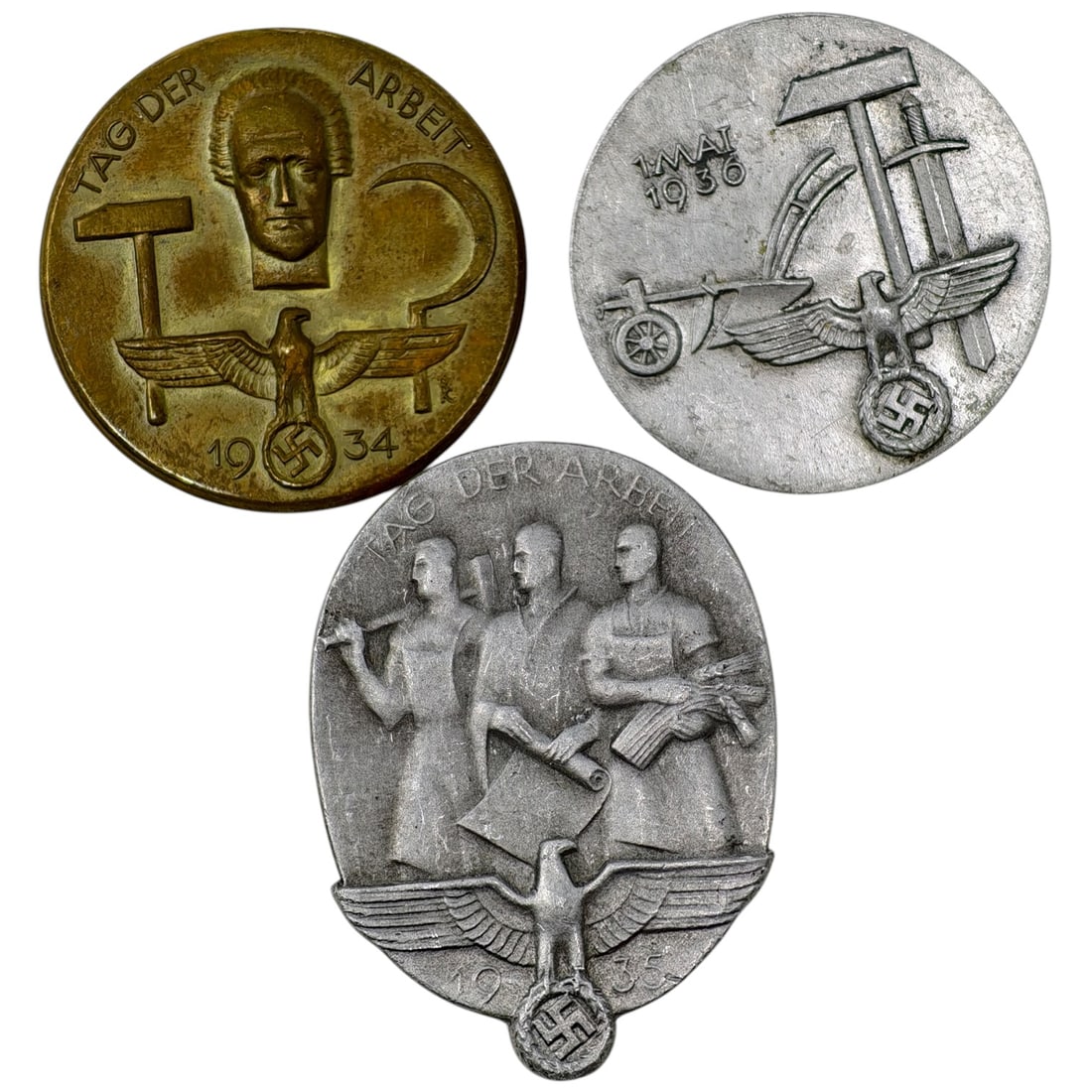 Third Reich Tinne Set: A set of tinnie badges commemorating National Labor Day (Tag der Arbeit): a 1934 example in what appears to be brass marked 'Paul Schmidt' with a portrait bust, hammer and sickle motif, and eagle; a