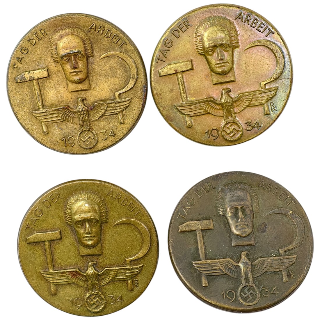 Third Reich Tinnie Set - 1934 Tag der Arbeit Badges: Set of pin-back commemorative badges (tinnies) marking the 1934 National Labor Day (Tag der Arbeit), produced by different regional manufacturers as evidenced by varied maker initials near the eagle.