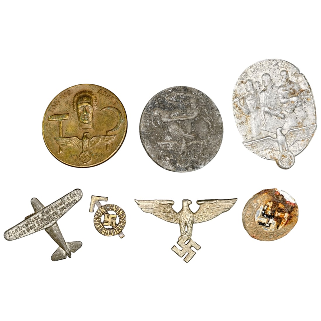 Third Reich Nazi Set of Tinnie Badges with Pins: A set of Third Reich era commemorative tinnies and pins, including a set of 'Tag der Arbeit' (Day of Labour) badges dated 1934, an aviation-themed pinback, a small enamel-style roundel with swastika,
