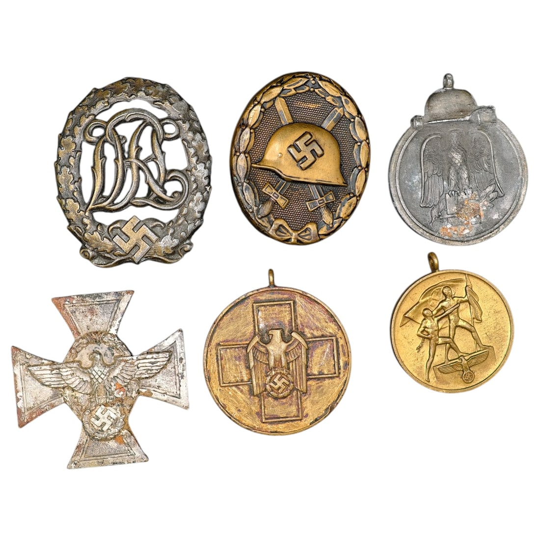 Third Reich Nazi Set of Badges and Medals: A grouping of a set of German WWII-era decorations: a DRL Sports Badge with swastika and oak leaf wreath; a Wound Badge featuring a helmet, crossed swords, and swastika within a wreath; a