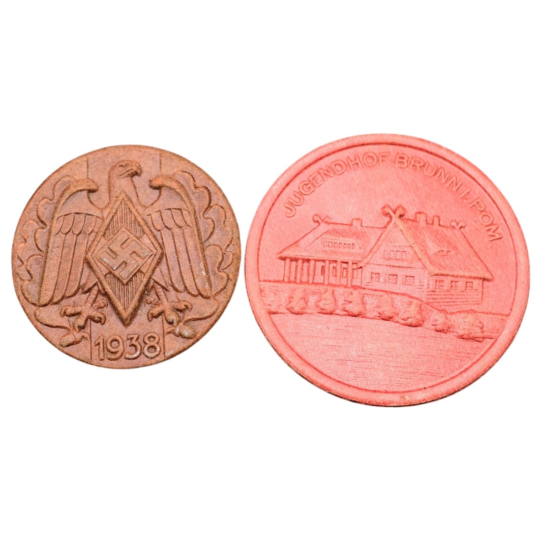 German WWII Hitler Youth 1938 Commemorative Tinnie Pair - Jugendhof Brunn/Pom.: A set of pressed-fiber/composition membership badges (tinnies). One depicts an eagle with swastika diamond emblem and date '1938', the other reads 'JUGENDHOF BRUNN I. POM.' with an image of a lodge-st