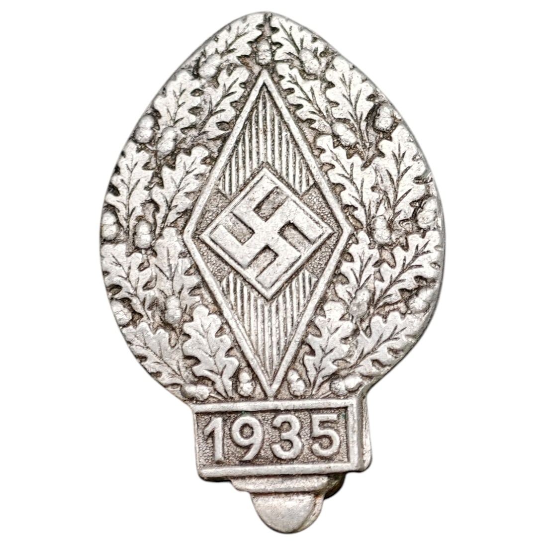 Hitler Youth Event Badge 1935: Tinnie-style badge featuring a central diamond-shaped HJ (Hitlerjugend) rune motif surrounded by an oak leaf and acorn wreath, with '1935' at the base. The reverse is die-stamped 'R. ZIMMERMANN STUTTG
