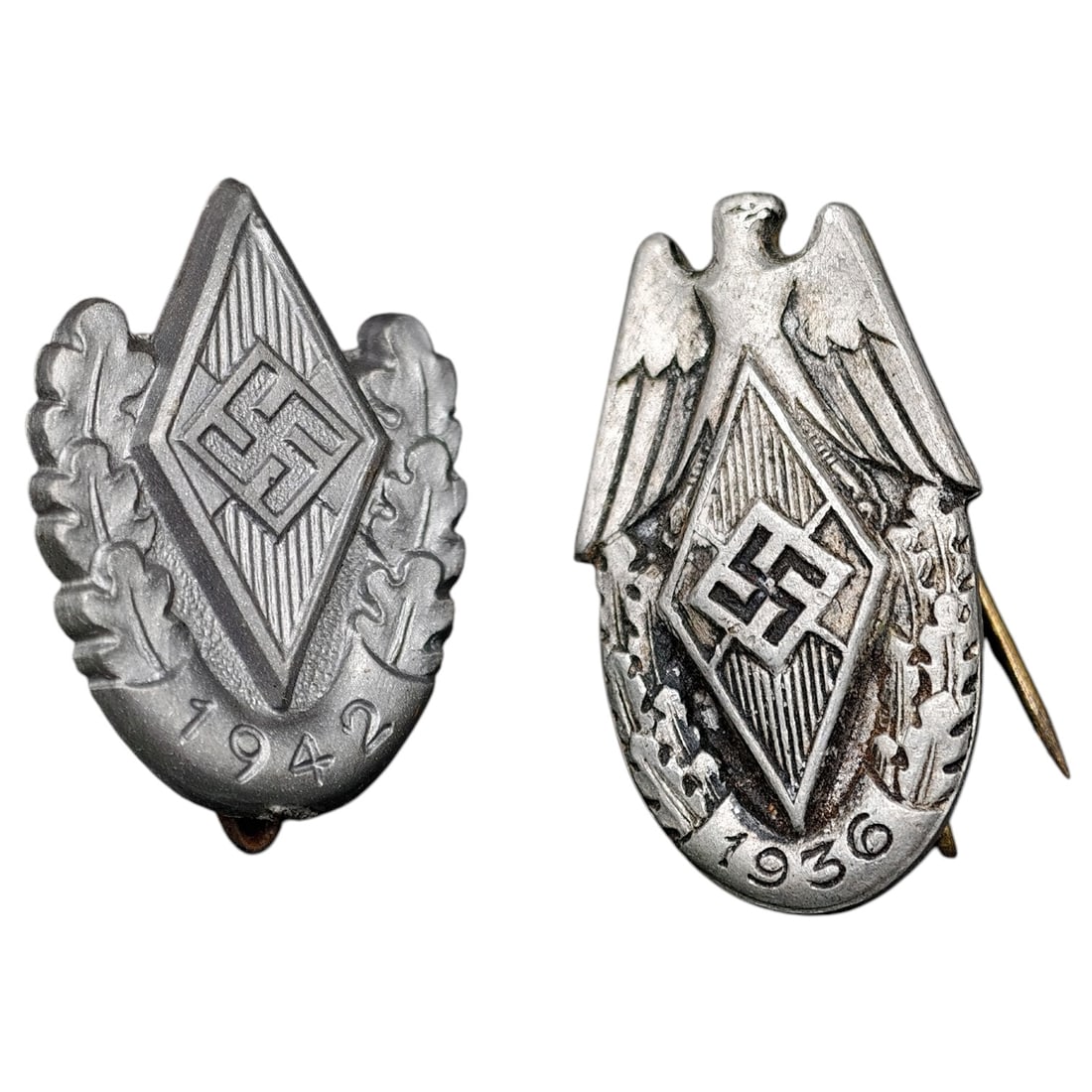 Hitler Youth (HJ) Pin Badges, 1936 and 1942 Dated - Pair: A pair of HJ Gaufuhrer/Sponsor-type pin badges (Gaudienstauszeichnung style), each featuring the HJ diamond emblem with oak leaf surround. One example is dated 1936 and features an eagle above the dia