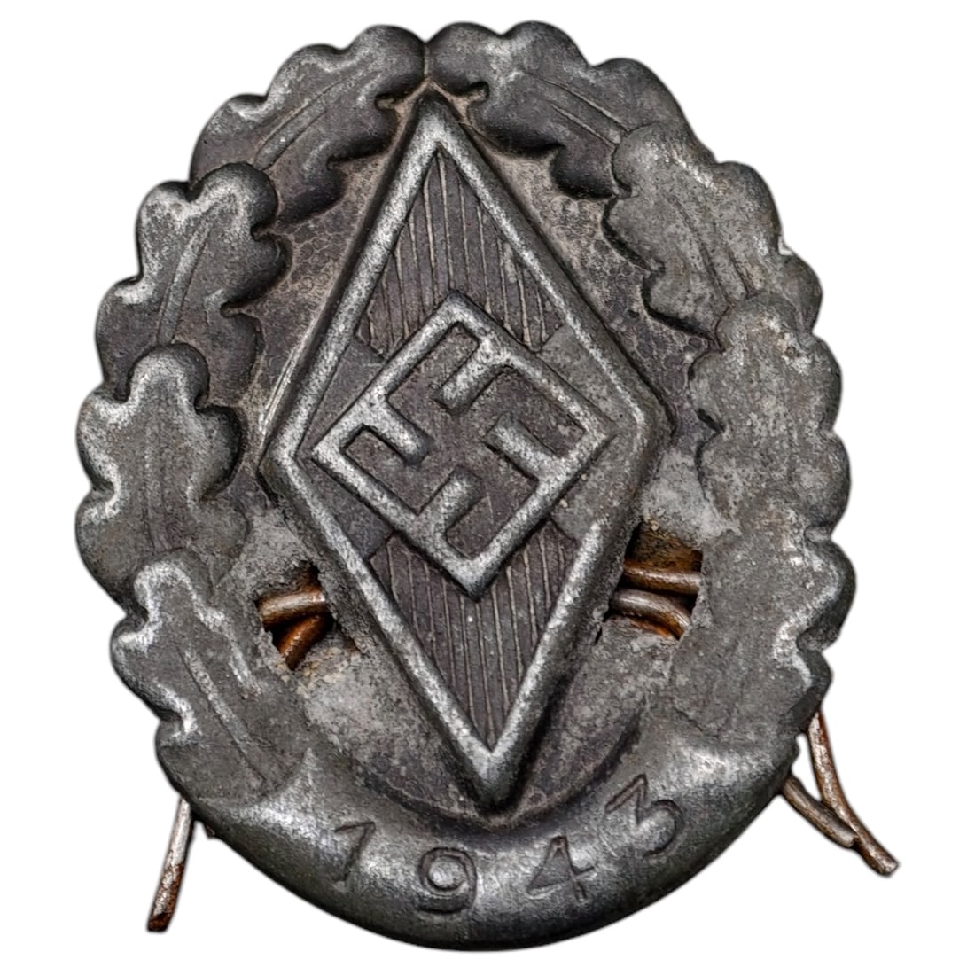 German WWII Wound Badge in Black: Cast metal badge featuring the HJ diamond emblem with swastika centered within an oak leaf wreath, dated "1943" at the base. Surface shows a dark grey/pewter-toned finish. No maker marks are visible i