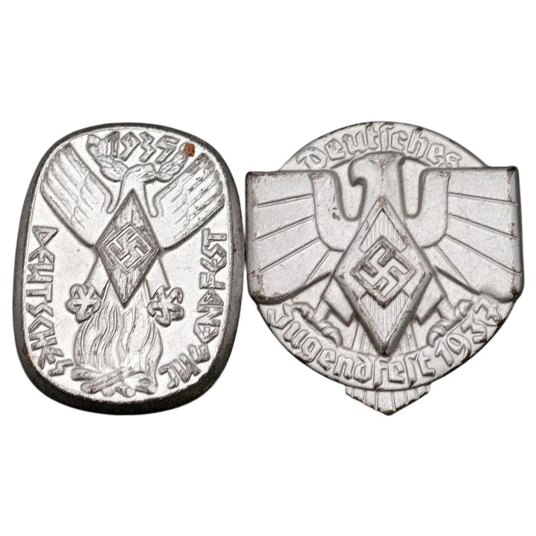 Third Reich Nazi Jugendfest 1935 and 1937 Tinnie Badges (Pair): A set of pin-back membership badges (tinnies) commemorating the "Deutsches Jugendfest" of 1935 and 1937, each featuring a stylized eagle with HJ diamond emblem and swastika. Both are die-struck in a m
