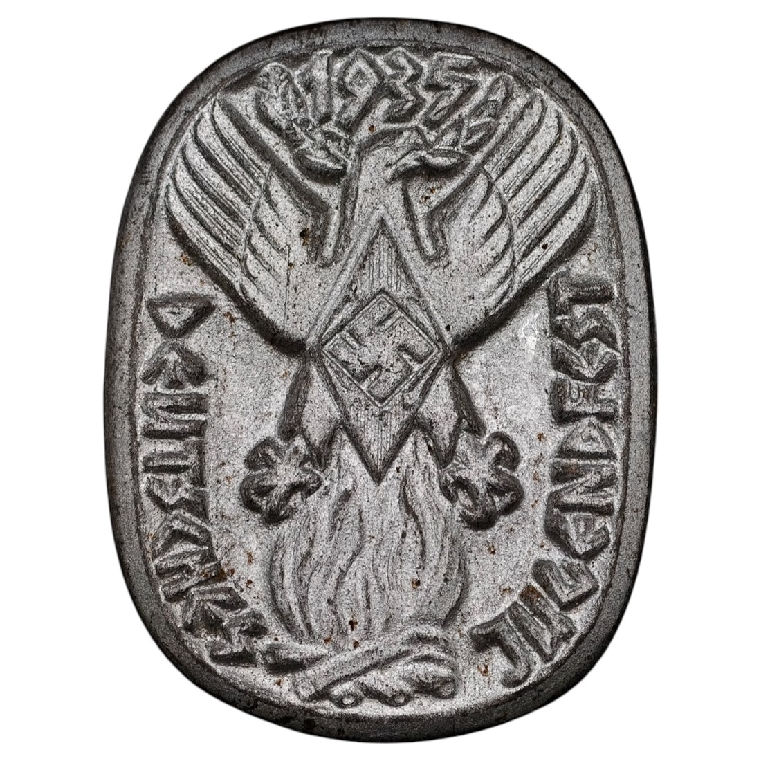 Third Reich Jugendfest 1935 Tinnie: A cast metal commemorative badge (tinnie) for the 1935 Deutsches Jugendfest, featuring an eagle above a diamond-shaped emblem with swastika over a stylized flame, flanked by the inscription 'DEUTSCHES
