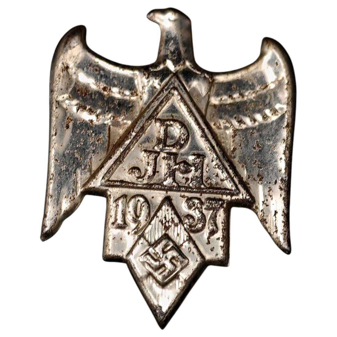 German Third Reich DJH 1937 Badge Tinnie: A stamped white-metal eagle-form badge, bearing the letters 'DJH' within a triangle, the date '1937' below, and a diamond with an eagle-and-swastika emblem at the base. Likely a commemorative event ba