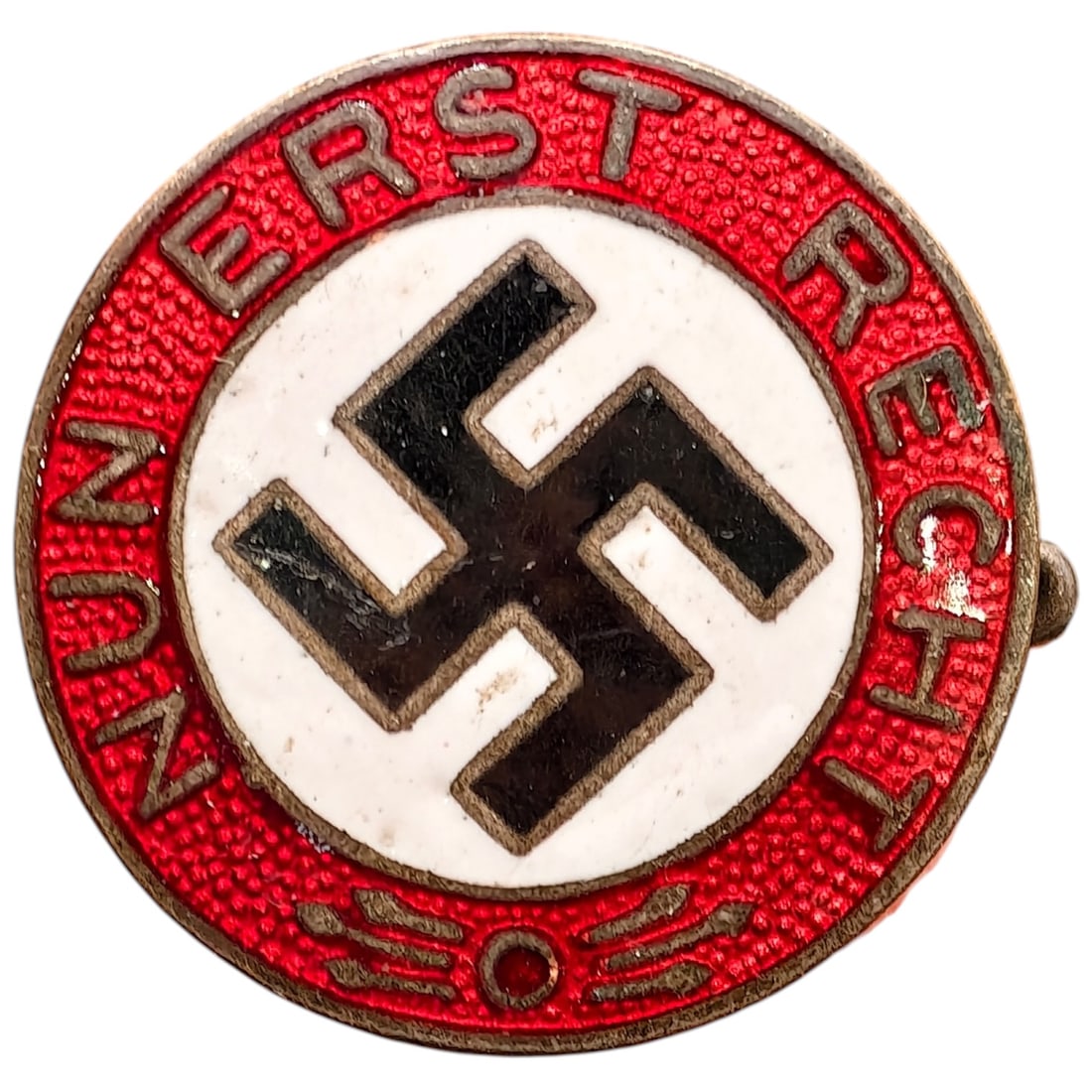 Early NSDAP Slogan Badge Nun Erst Recht: A round enamel membership/slogan badge featuring a central white enameled disc with black mobile swastika, surrounded by a red enamel band with raised lettering reading "NUN ERST RECHT".