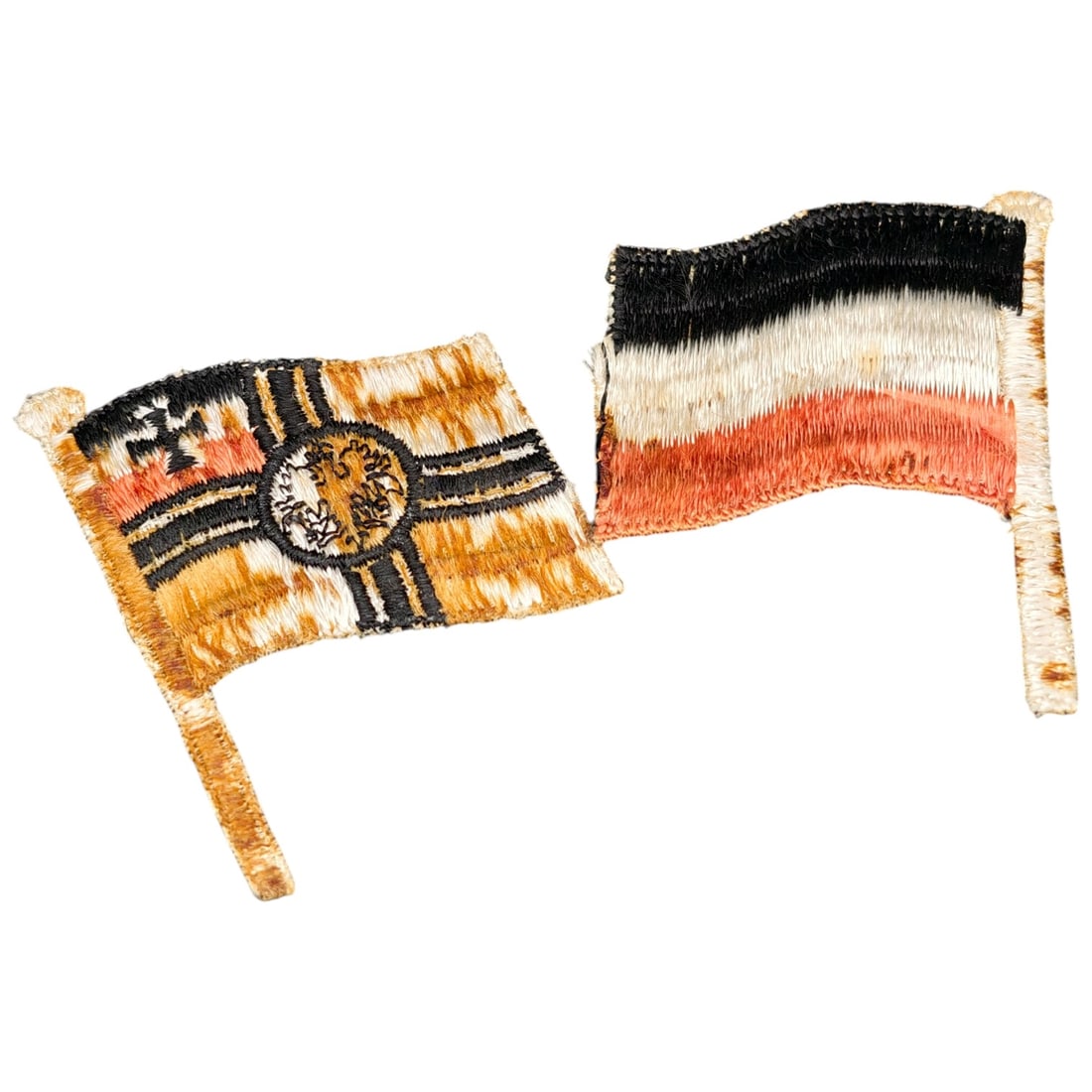 Imperial German WWI Embroidered Crossed Flags Patch: A woven/embroidered cloth patch depicting two crossed Imperial German flags on staffs: the Kaiserliche Marine (Imperial Naval Jack) with Iron Cross and central Reichsadler roundel, paired with the