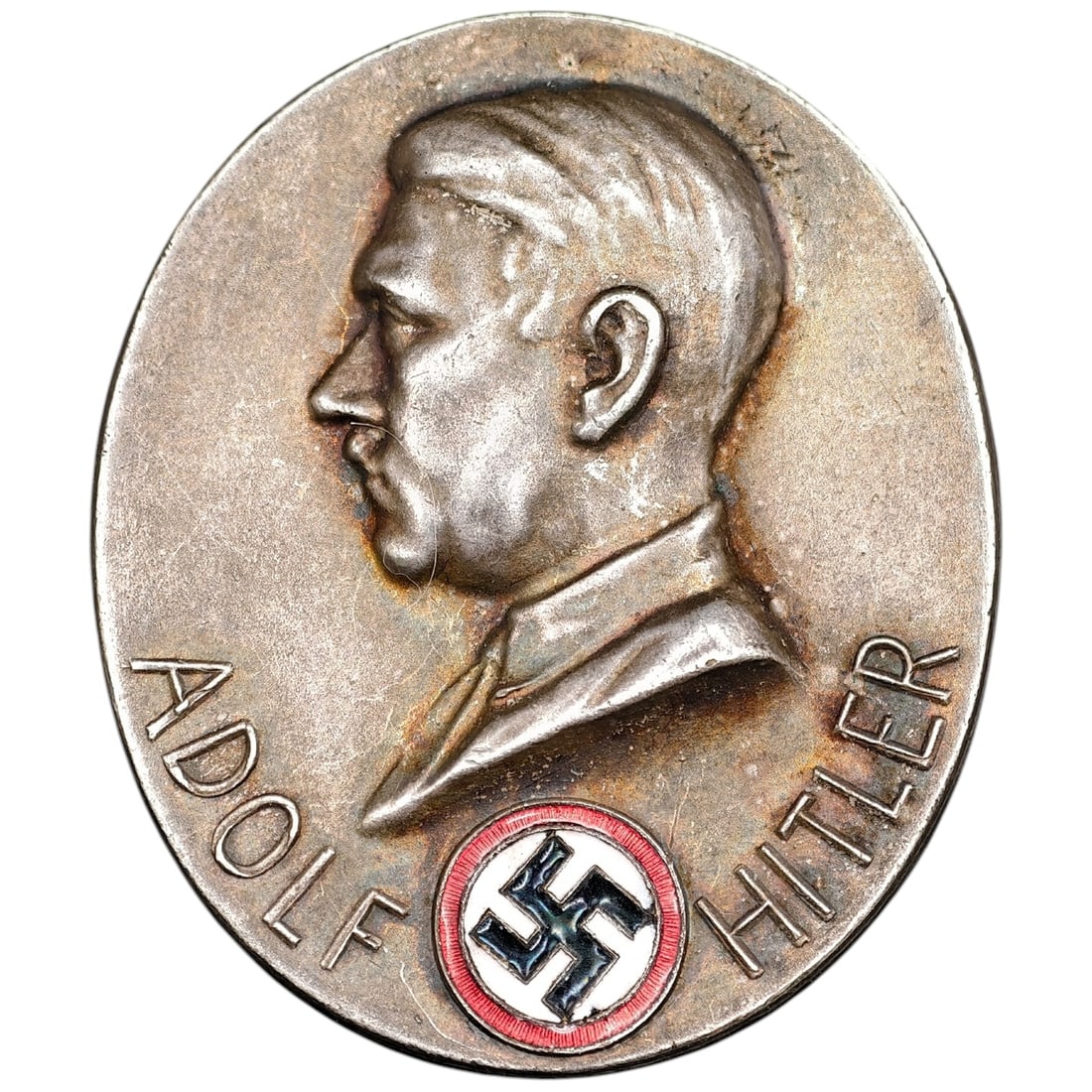 Early NSDAP Adolf Hitler Badge: An oval commemorative badge/tinnie featuring a raised profile portrait of Adolf Hitler with 'ADOLF HITLER' in raised lettering below, alongside an enameled NSDAP swastika roundel in red, white, and