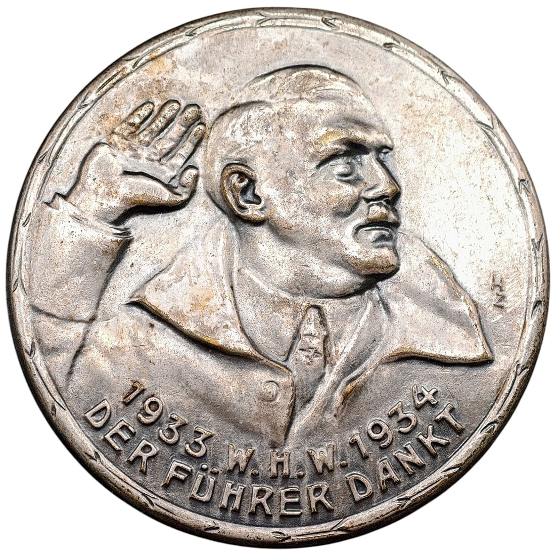 Adolf Hitler 1933-1934 WHW 'Der Führer Dankt' Badge: A single-piece cast medallic badge commemorating the 1933-1934 Winterhilfswerk (WHW) charity drive, with the inscription "1933 W.H.W. 1934 DER FÜHRER DANKT" (The Führer Thanks You). Obverse depicts