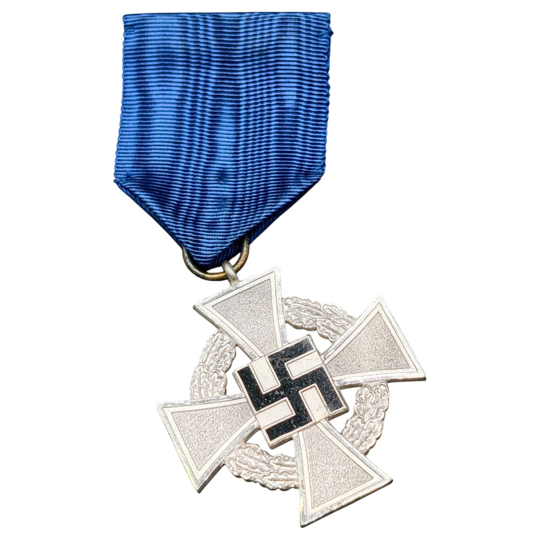 25 Year Faithful Service Medal - Third Reich Nazi Era Medal: A cross-form medal in what appears to be silvered metal with oak leaf wreath motifs between the arms, mounted with a central raised swastika finished in black enamel. The reverse bears the inscribed m