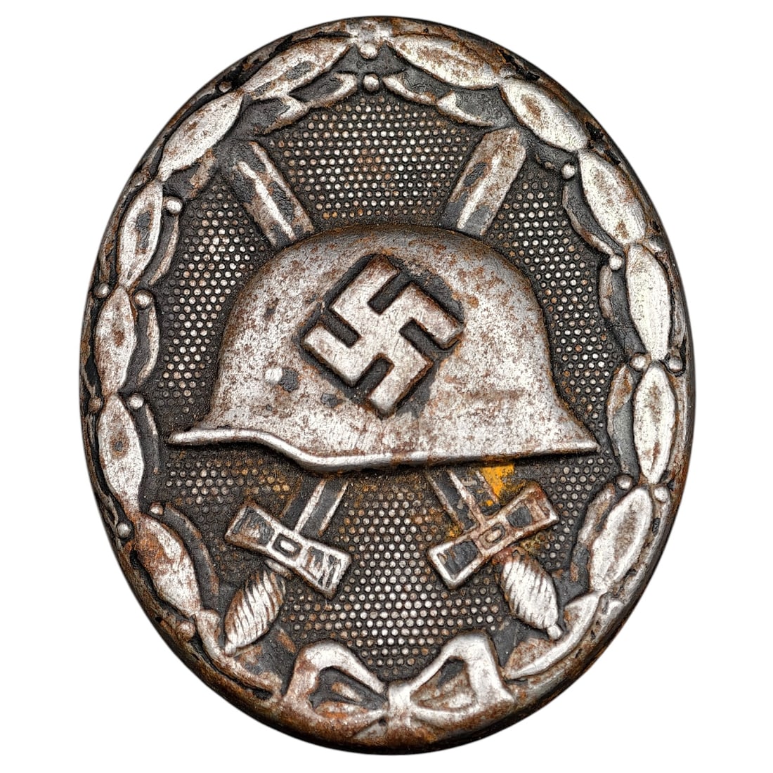Wound Badge in Black – Third Reich Nazi Era Medal Badge: A Third Reich Wound Badge (Verwundetenabzeichen) in what appears to be black grade, depicting a steel helmet over a swastika, flanked by crossed swords, within a wreath border.