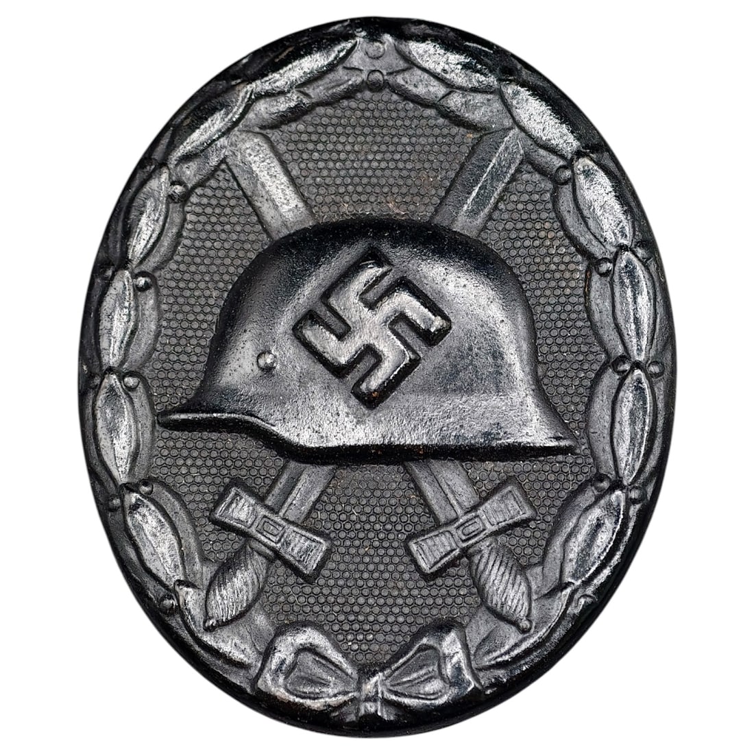 Wound Badge in Black – Third Reich Nazi Era Medal Badge: A Third Reich Wound Badge (Verwundetenabzeichen) in what appears to be black grade, depicting a steel helmet over a swastika, flanked by crossed swords, within a wreath border.