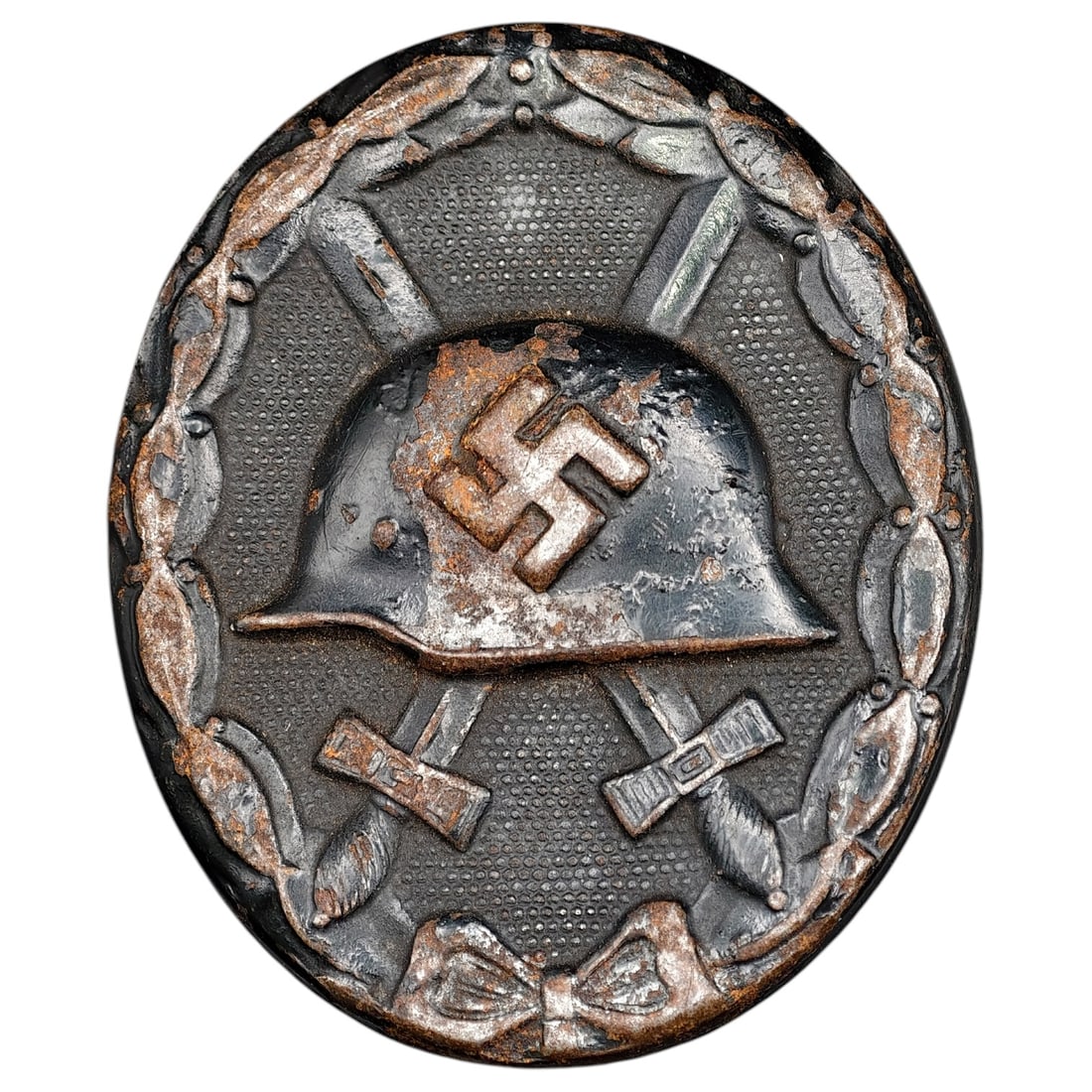 Wound Badge in Black – Third Reich Nazi Era Medal Badge: A Third Reich Wound Badge (Verwundetenabzeichen) in what appears to be black grade, depicting a steel helmet over a swastika, flanked by crossed swords, within a wreath border.