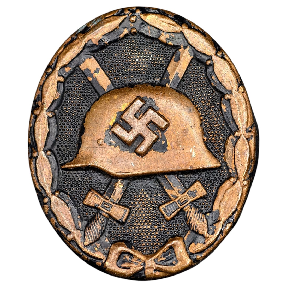 Wound Badge in Black – Third Reich Nazi Era Medal Badge: A Third Reich Wound Badge (Verwundetenabzeichen) in what appears to be black grade, depicting a steel helmet over a swastika, flanked by crossed swords, within a wreath border.
