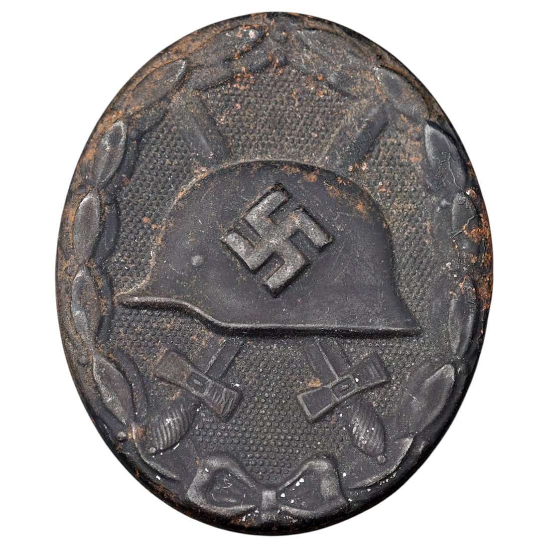 Wound Badge in Black – Third Reich Nazi Era Medal Badge: A Third Reich Wound Badge (Verwundetenabzeichen) in what appears to be black grade, depicting a steel helmet over a swastika, flanked by crossed swords, within a wreath border.