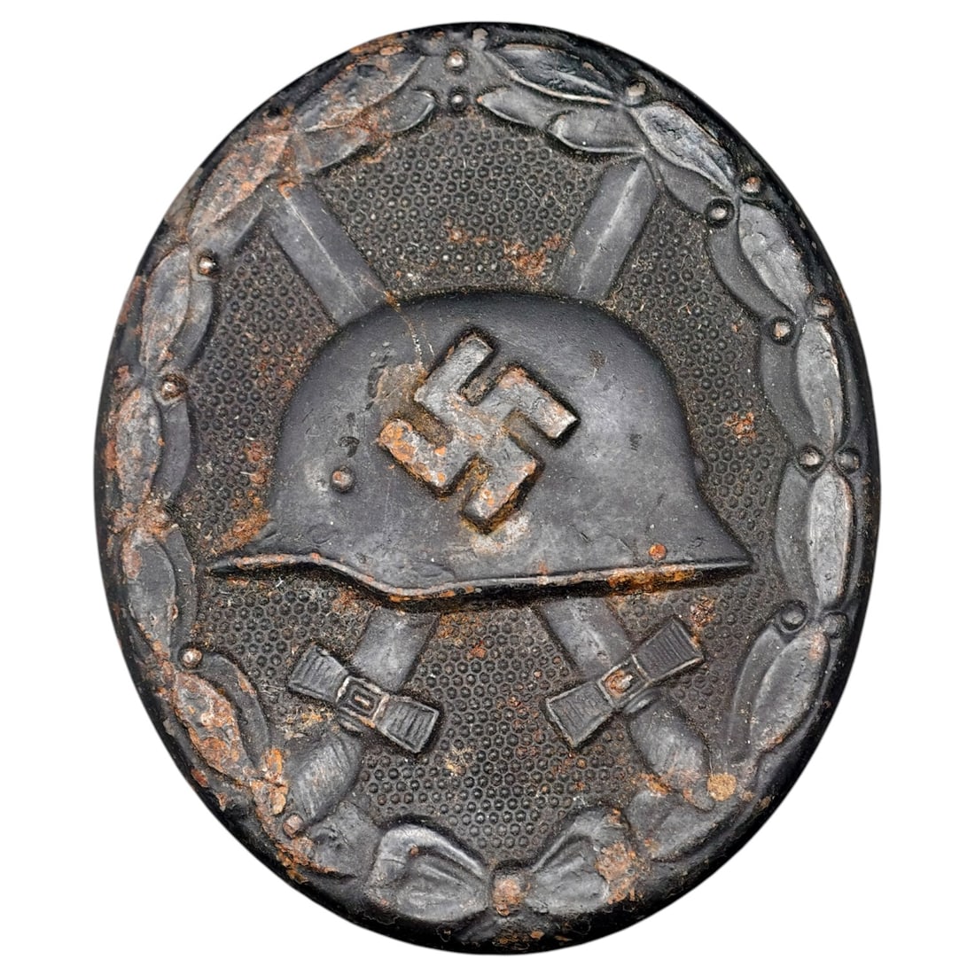 Wound Badge in Black – Third Reich Nazi Era Medal Badge: A Third Reich Wound Badge (Verwundetenabzeichen) in what appears to be black grade, depicting a steel helmet over a swastika, flanked by crossed swords, within a wreath border.