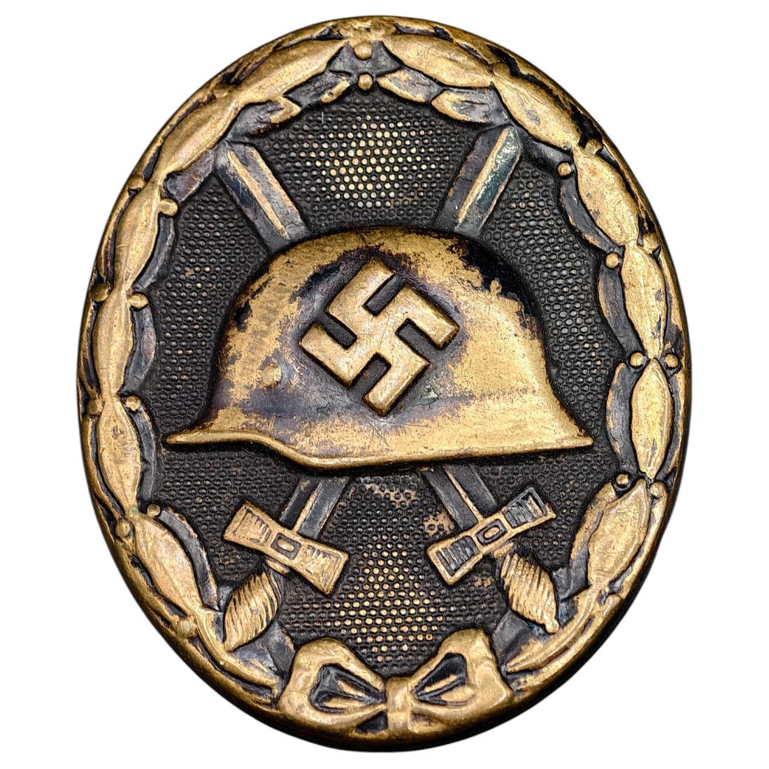 Wound Badge in Black – Third Reich Nazi Era Medal Badge: A Third Reich Wound Badge (Verwundetenabzeichen) in what appears to be black grade, depicting a steel helmet over a swastika, flanked by crossed swords, within a wreath border.