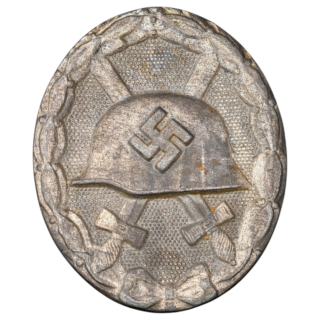 Third Reich Nazi Wound Badge in Silver: A Wound Badge in a silver grade featuring a stahlhelm over crossed swords with a swastika, surrounded by a laurel wreath tied at the base with a ribbon bow.
