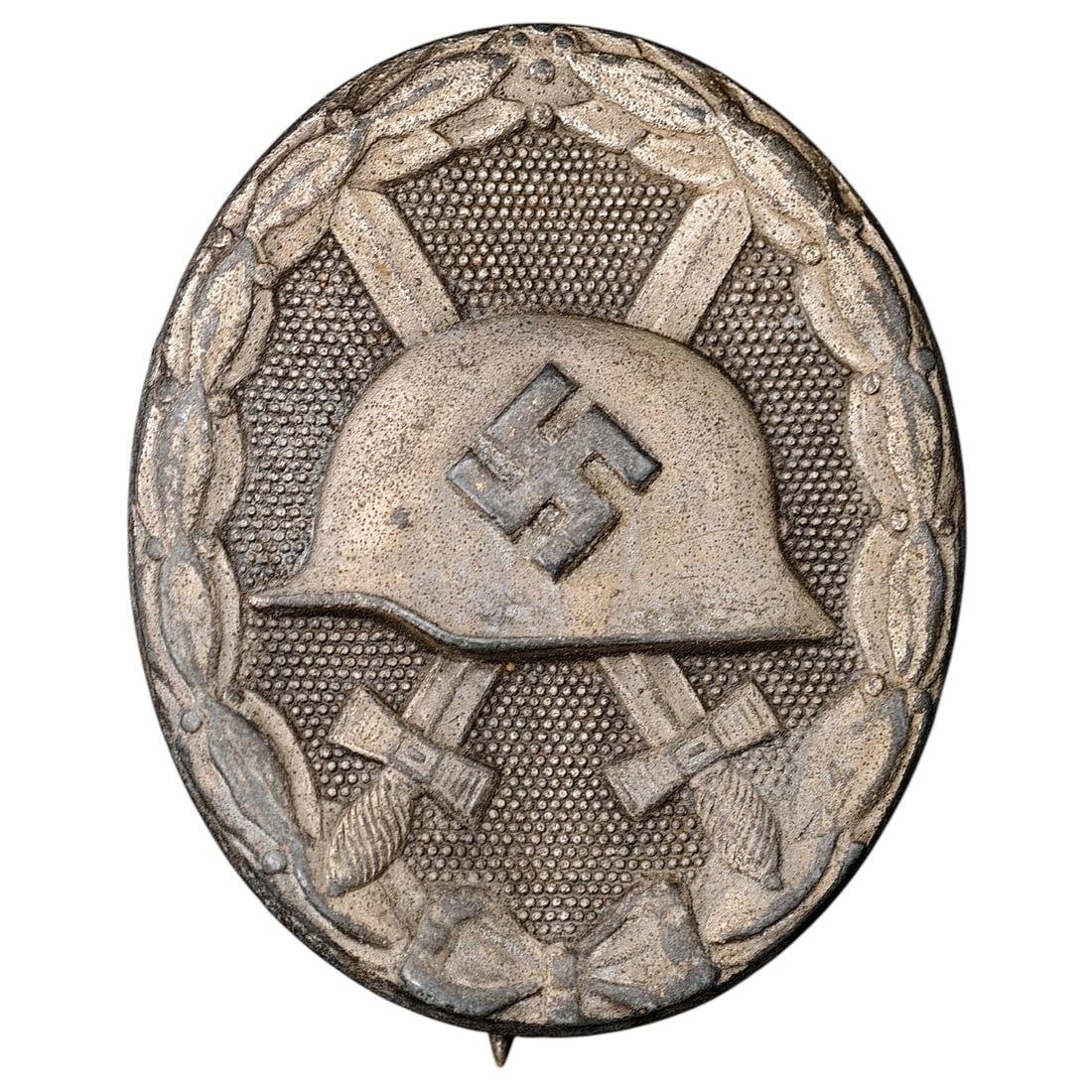 Third Reich Nazi Wound Badge in Silver: A Wound Badge in a silver grade featuring a stahlhelm over crossed swords with a swastika, surrounded by a laurel wreath tied at the base with a ribbon bow.