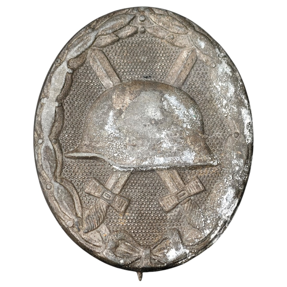Third Reich Nazi Wound Badge in Silver: A Wound Badge in a silver grade featuring a stahlhelm over crossed swords with a swastika, surrounded by a laurel wreath tied at the base with a ribbon bow.
