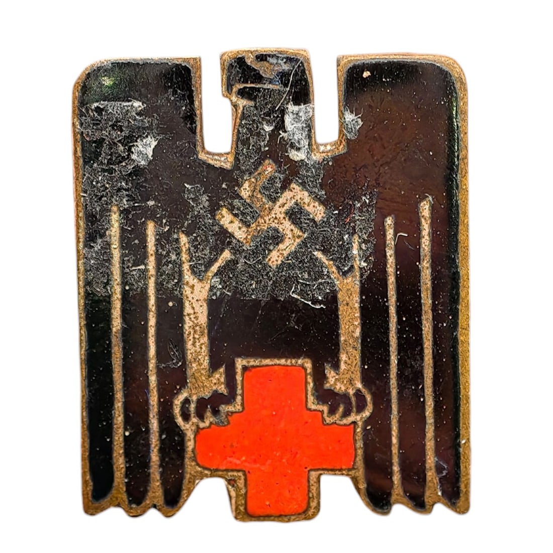 Third Reich Nazi Red Cross Pin: A small enameled pin badge in the form of a stylized eagle with swastika above a red enamel cross, worn by German Red Cross (DRK) members or supporters.