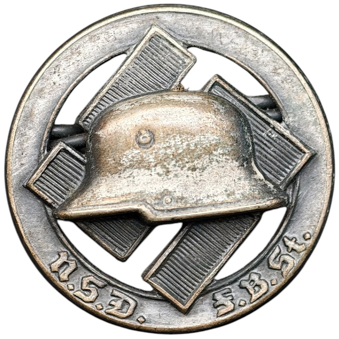 Third Reich Nazi NSD FBST Stahlhelm Pin Badge: A round pin badge featuring a stylized steel helmet (Stahlhelm) over a swastika motif, encircled by an outer ring bearing the inscription "N.S.D. F.B.St." referencing the Nationalsozialistischer Deuts