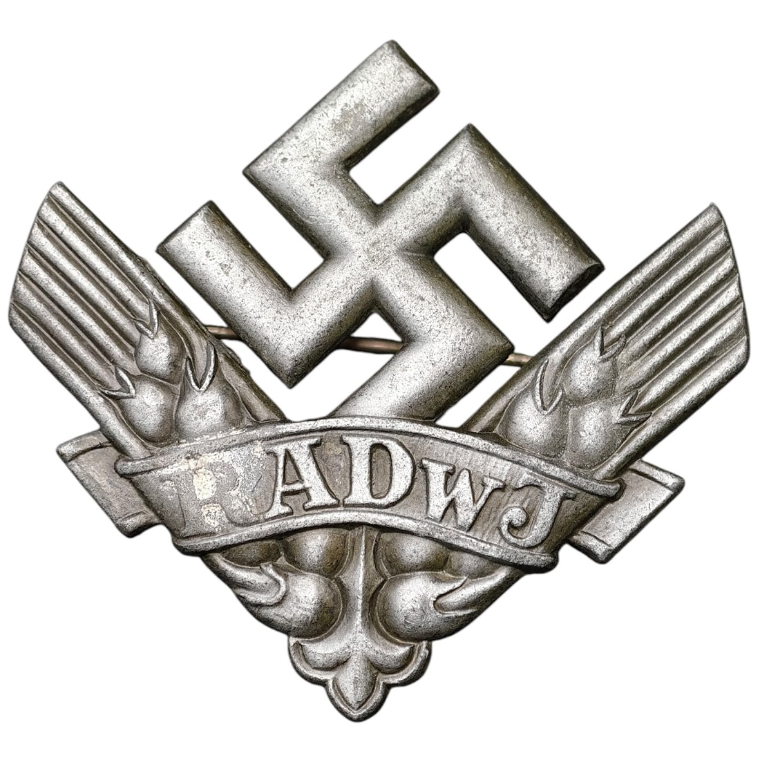 Third Reich RadwJ Brooch: A stamped brooch in what appears to be white metal for the Reichsarbeitsdienst der weiblichen Jugend (RADwJ - Female Labor Service), featuring a mobile swastika above crossed wheat sheaves and a banne