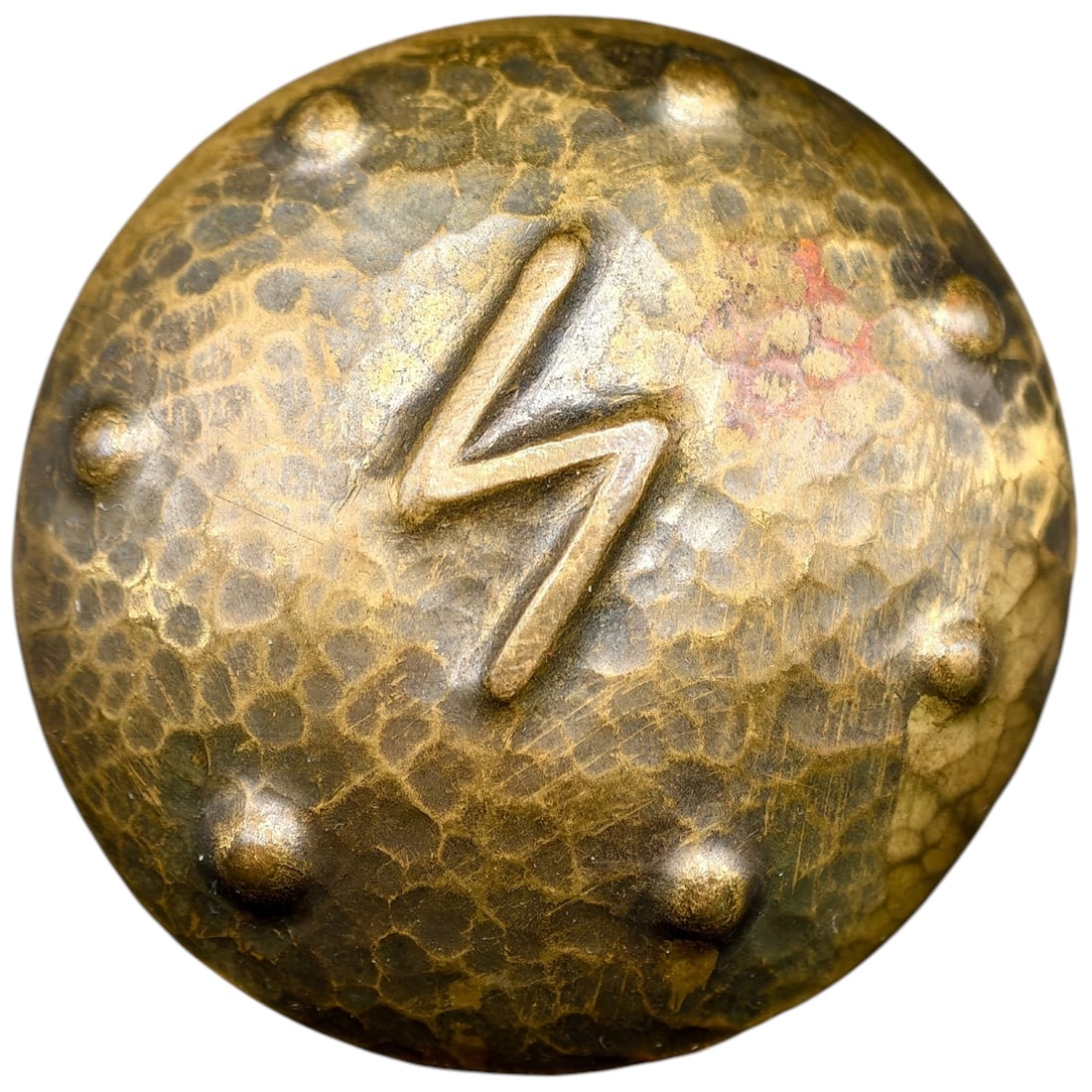 German WWII-Era Rune Brooch (Sig Rune): A domed item in what appears to be brass with hammered surface texture and a raised 'Sig' rune (lightning-bolt symbol) at center, bordered by a ring of applied dome studs.