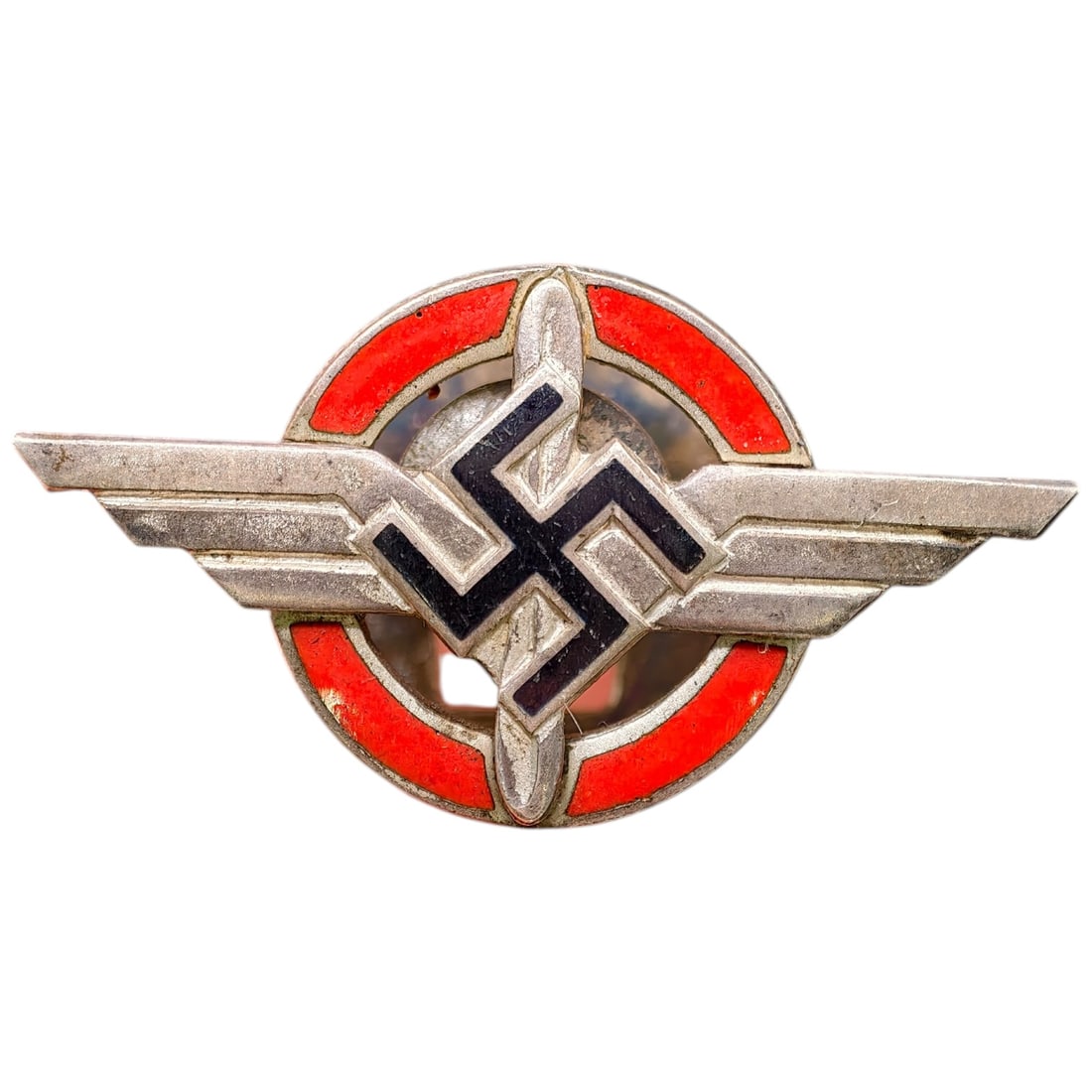 Third Reich Nazi DLV Pin: A winged badge with central mobile swastika device flanked by red enamel segments, mounted with stylized wings. Reverse engraved with personalization reading "DER KUNSCHTMALER 12.11.33," likely a peri
