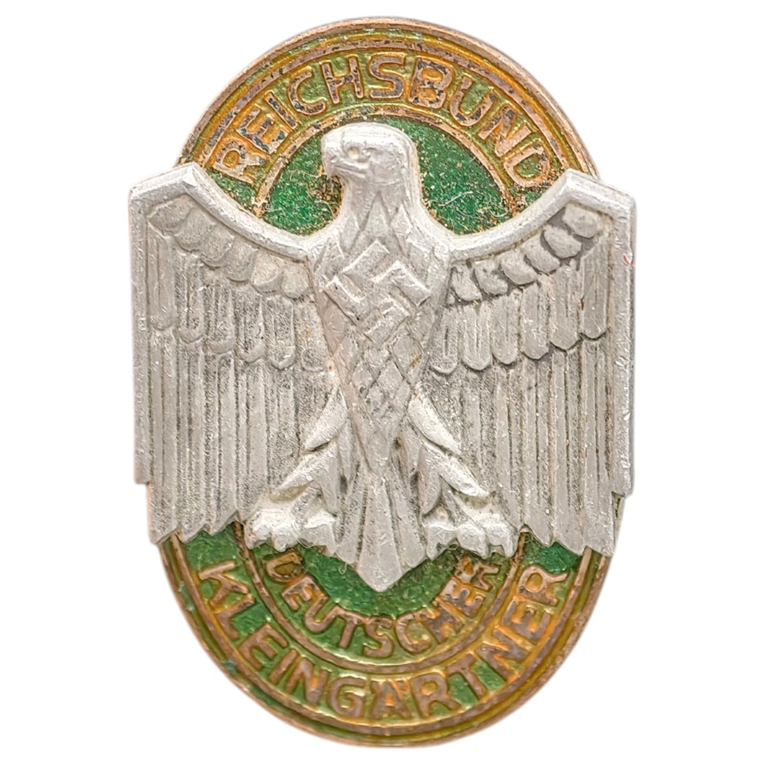 German WWII Reichsbund Deutscher Kleingartner Badge: Oval membership badge for the Reichsbund der Kleingärtner (Reich Federation of Small Gardeners), featuring a stamped eagle and swastika in what appears to be white metal on a green enamel field borde