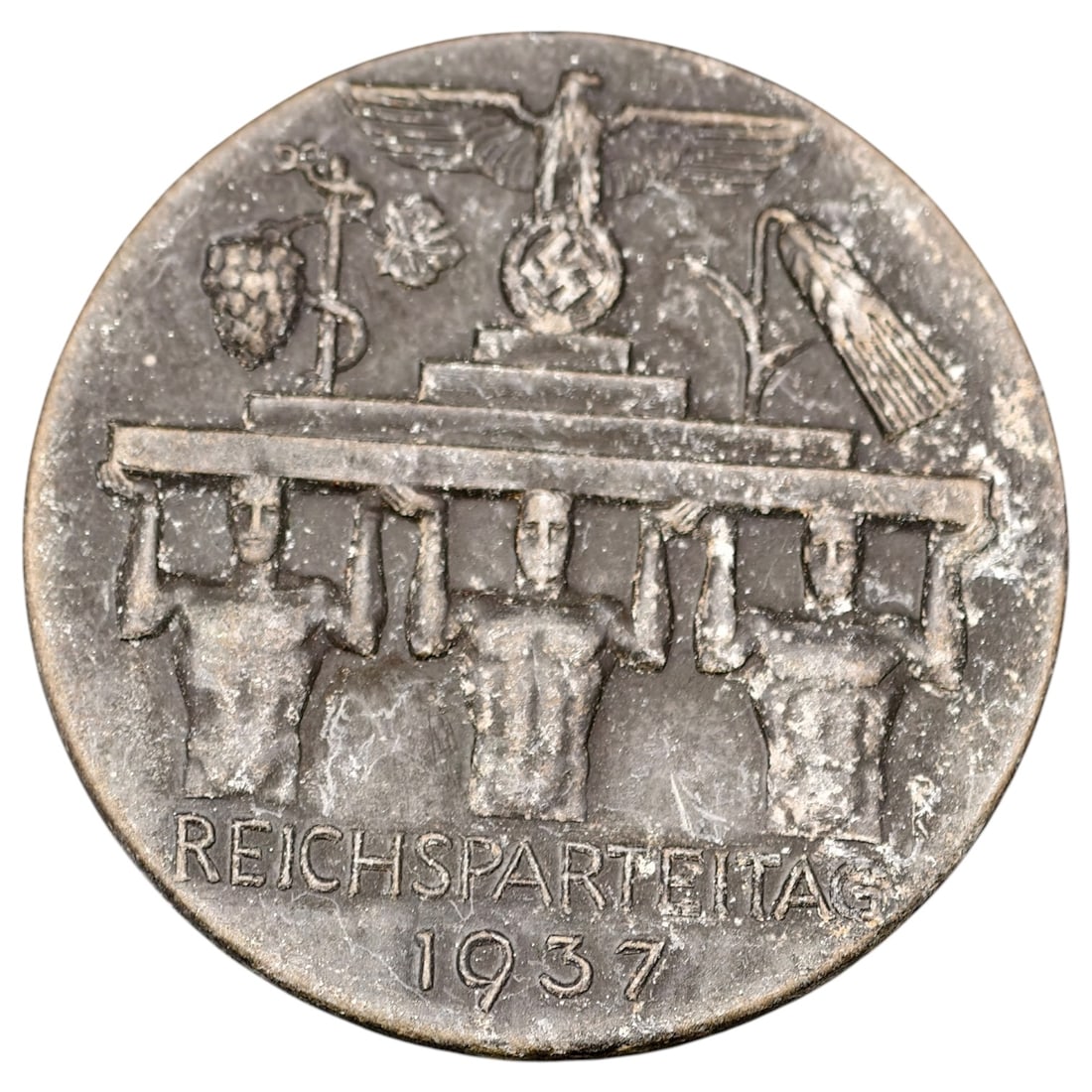 Third Reich Nazi Reichsparteitag 1978 Tinnie Badge: A commemorative pin-back tinnie for the 1937 Reichsparteitag (Nazi Party Rally), depicting a set of standard-bearers supporting a platform bearing a Reich eagle atop a swastika, flanked by regional co