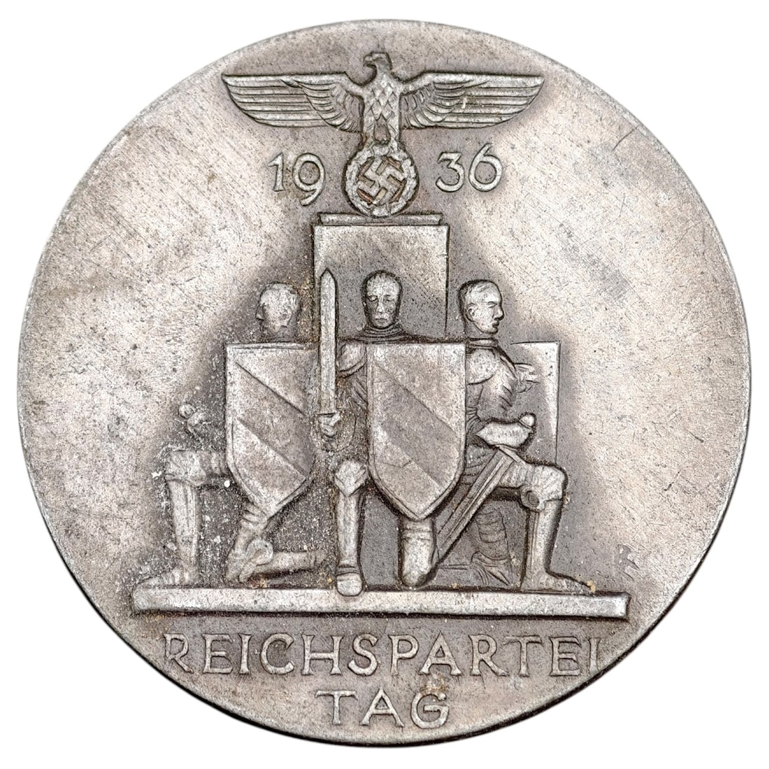 Third Reich Nazi Reichsparteitag 1936 Tinnie Badge: A round tinnie badge commemorating the 1936 Reichsparteitag (Nazi Party Rally at Nuremberg), featuring a Party eagle above a set of standard-bearers with shields, and the inscription 'REICHSPARTEITAG'