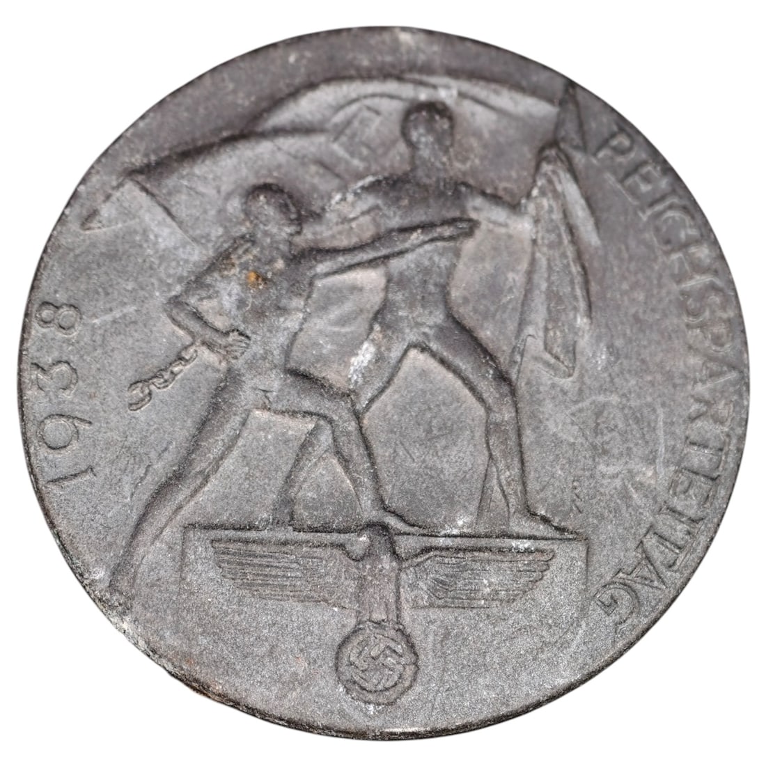 German Third Reich 1938 Reichsparteitag Tinnie Badge: A round tinnie (membership/commemorative badge) marked "1938" and "REICHSPARTEITAG" around the rim, depicting two figures with a broken chain standing before a flag, with an eagle and swastika emblem 
