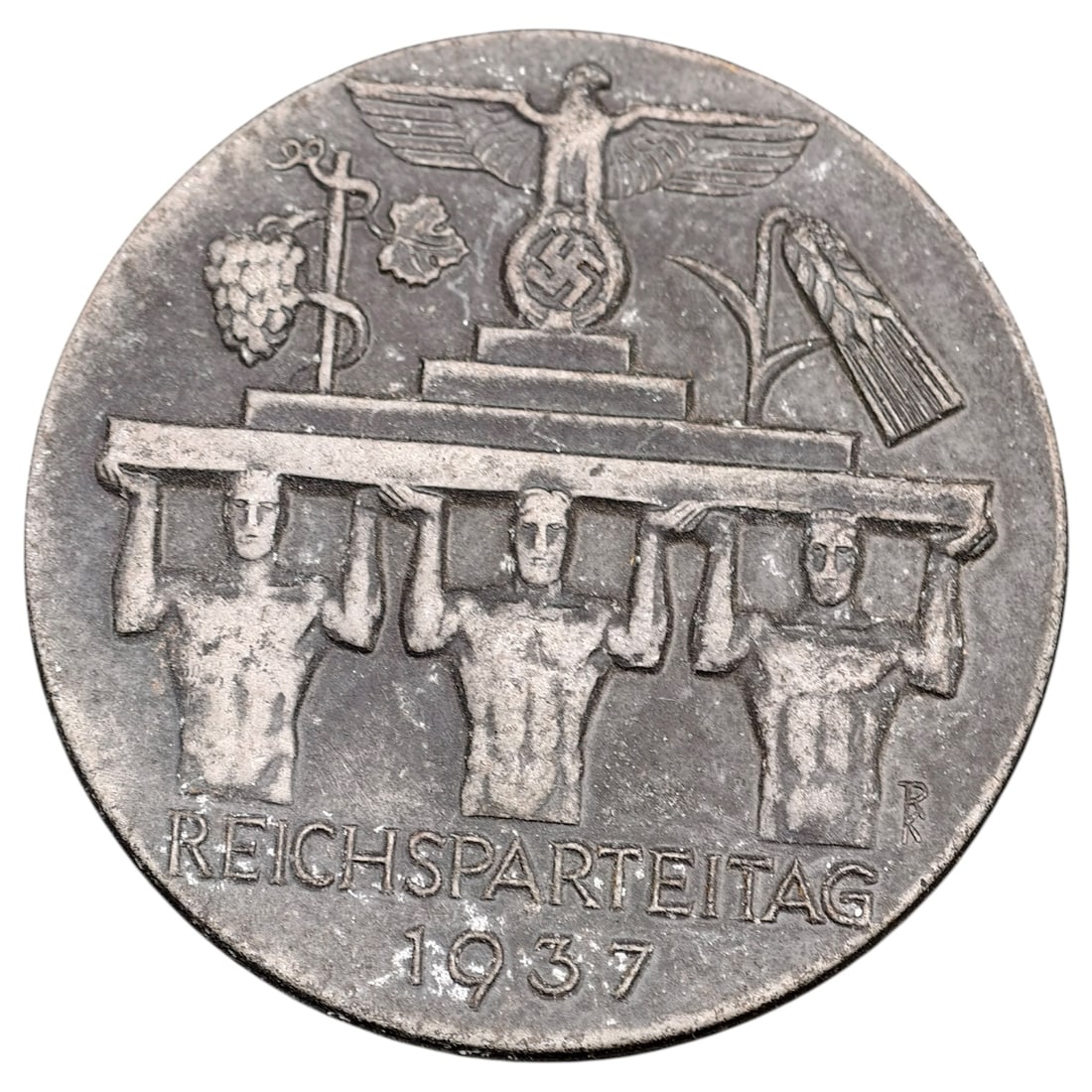 Third Reich Nazi Reichsparteitag 1937 Tinnie Badge: A pin-back commemorative tinnie for the 1937 Nazi Party Rally (Reichsparteitag), depicting three bare-chested figures carrying a stone platform surmounted by a Reich eagle with wreathed swastika, flan