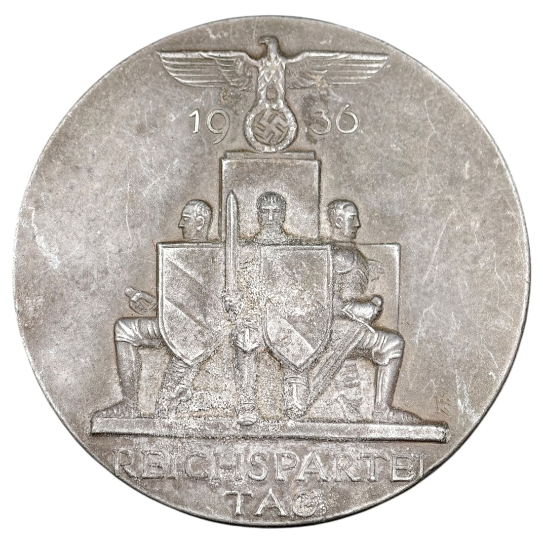 Third Reich Nazi Reichsparteitag 1936 Badge - Heavy Variant: A pin-back tinnie commemorating the 1936 Reichsparteitag (Nazi Party Rally) held in Nuremberg, depicting a set of standard bearers before a plinth surmounted by a Parteiadler (party eagle) over the da