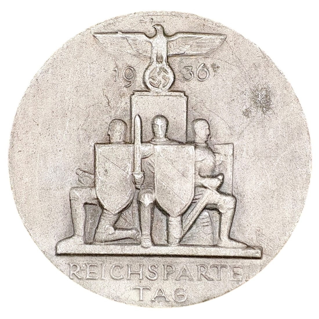 NSDAP Reichsparteitag 1936 Badge: A cast metal membership/event badge commemorating the 1936 Reichsparteitag, depicting a set of kneeling figures with shields flanking a central sword-bearing figure beneath a Party eagle and pillar in