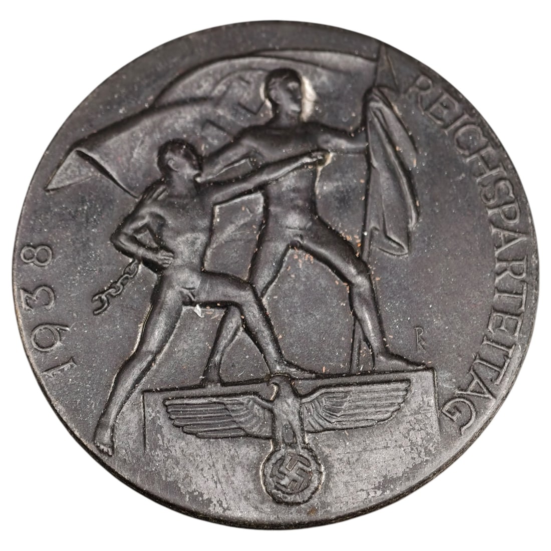 German WWII Reichsparteitag 1938 Tinnie Badge: A commemorative tinnie badge for the 1938 Reichsparteitag (Nazi Party Rally), depicting two figures with a breaking chain, a flag, and a Reich eagle emblem, with 'REICHSPARTEITAG' and '1938' inscribed