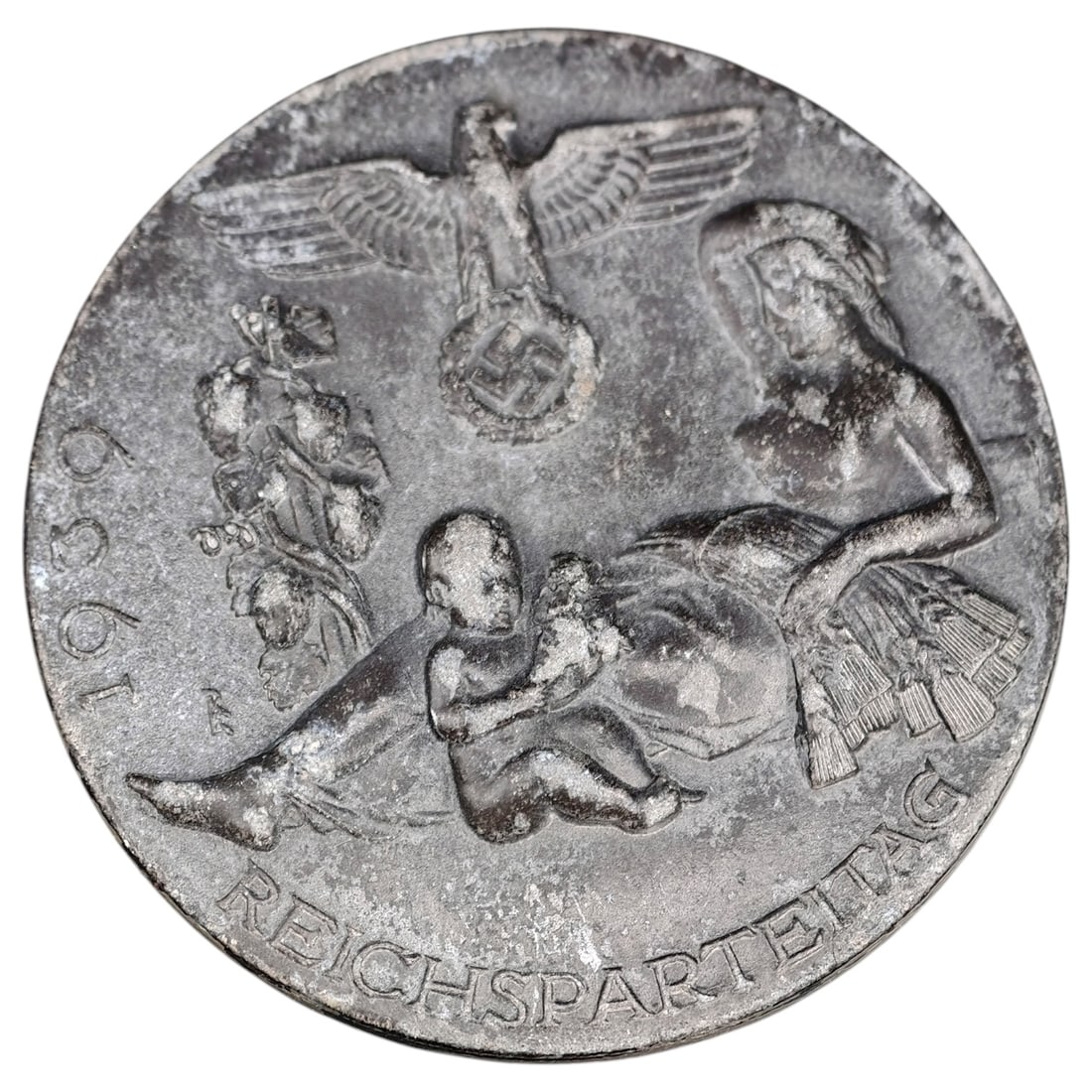 Third Reich Nazi Reichsparteitag 1939 Tinnie Badge: A pin-back tinnie commemorating the 1939 Reichsparteitag (Nazi Party Rally at Nuremberg), featuring an eagle over a wreathed swastika above a mother-and-child motif with 'REICHSPARTEITAG' and '1939' i