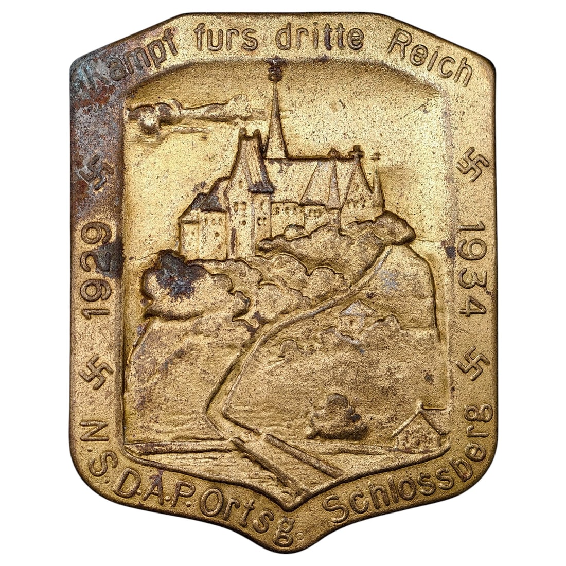 German NSDAP Tinnie Badge "Kampf furs dritte Reich" - N.S.D.A.P. Ortsg. Schlossberg 1929-1934: A shield-shaped commemorative tinnie badge issued by the NSDAP local group (Ortsgruppe) of Schlossberg, marking the period 1929-1934. The obverse depicts a hilltop castle scene with a winding path, fl