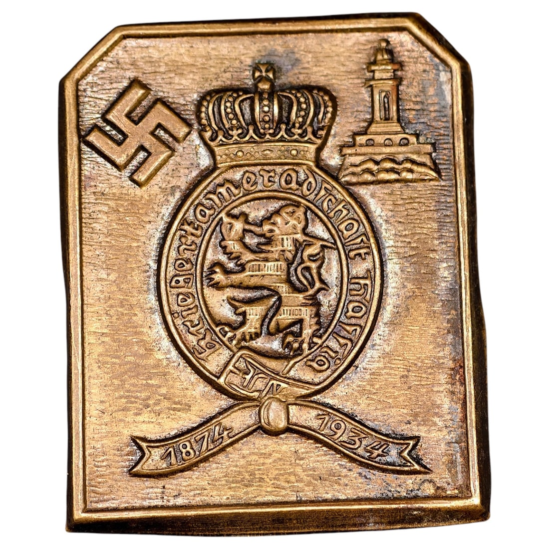 German 1934 Commemorative Plaque/Tinnie with Crown, Lion Crest and Lighthouse Motif: A cast bronze-toned commemorative plaque or tinnie, dated "1874-1934" on a ribbon banner, featuring a royal crown above a shield with a rampant lion and Latin motto, flanked by a lighthouse tower and