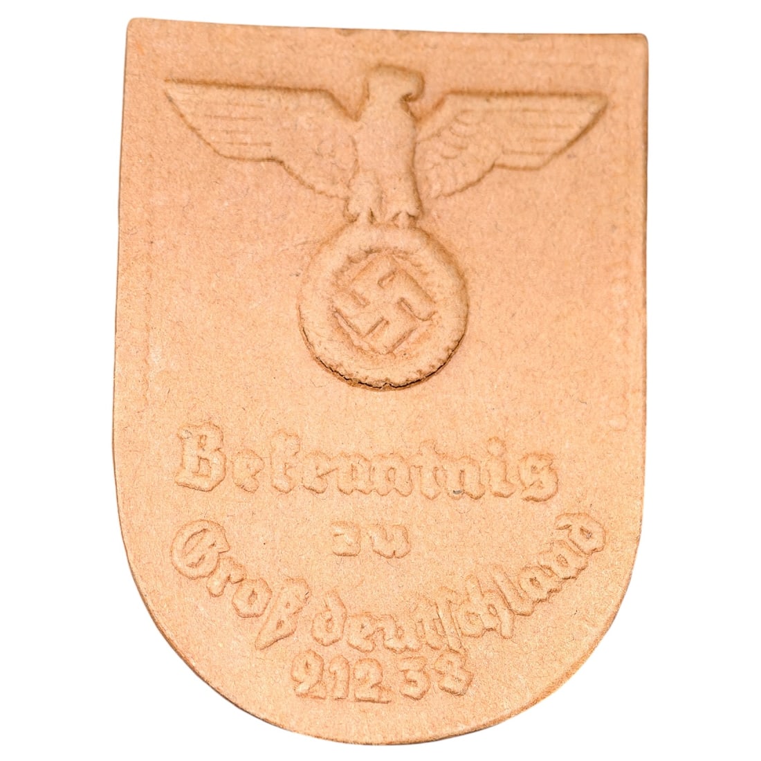 German WWII Political Tinnie - "Bekenntnis zu Großdeutschland" 1938 Badge: A pressed tinnie/badge shield-shaped, embossed with an eagle atop a wreathed swastika above the inscription "Bekenntnis zu Großdeutschland 21.2.38" ("Commitment to Greater Germany"), commemorating