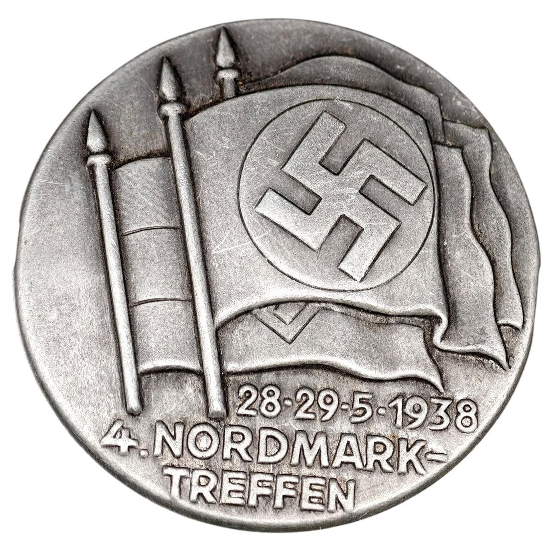 Third Reich 4. Nordmark-Treffen 1938 Tinnie Badge: A pin-back tinnie (rally badge) commemorating the 4th Nordmark regional meeting, dated 28-29.5.1938. The obverse depicts a flag bearing a swastika within a circle flanked by two banner-topped standard
