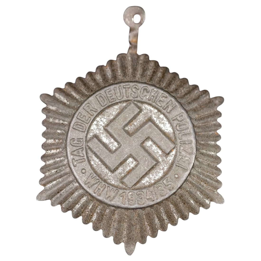 Third Reich Police Badge: A pressed badge in what appears to be white metal, sunburst commemorative badge for the 'Tag der Deutschen Polizei' (Day of the German Police), inscribed 'TAG DER DEUTSCHEN POLIZEI - WHW 1934/35' arou