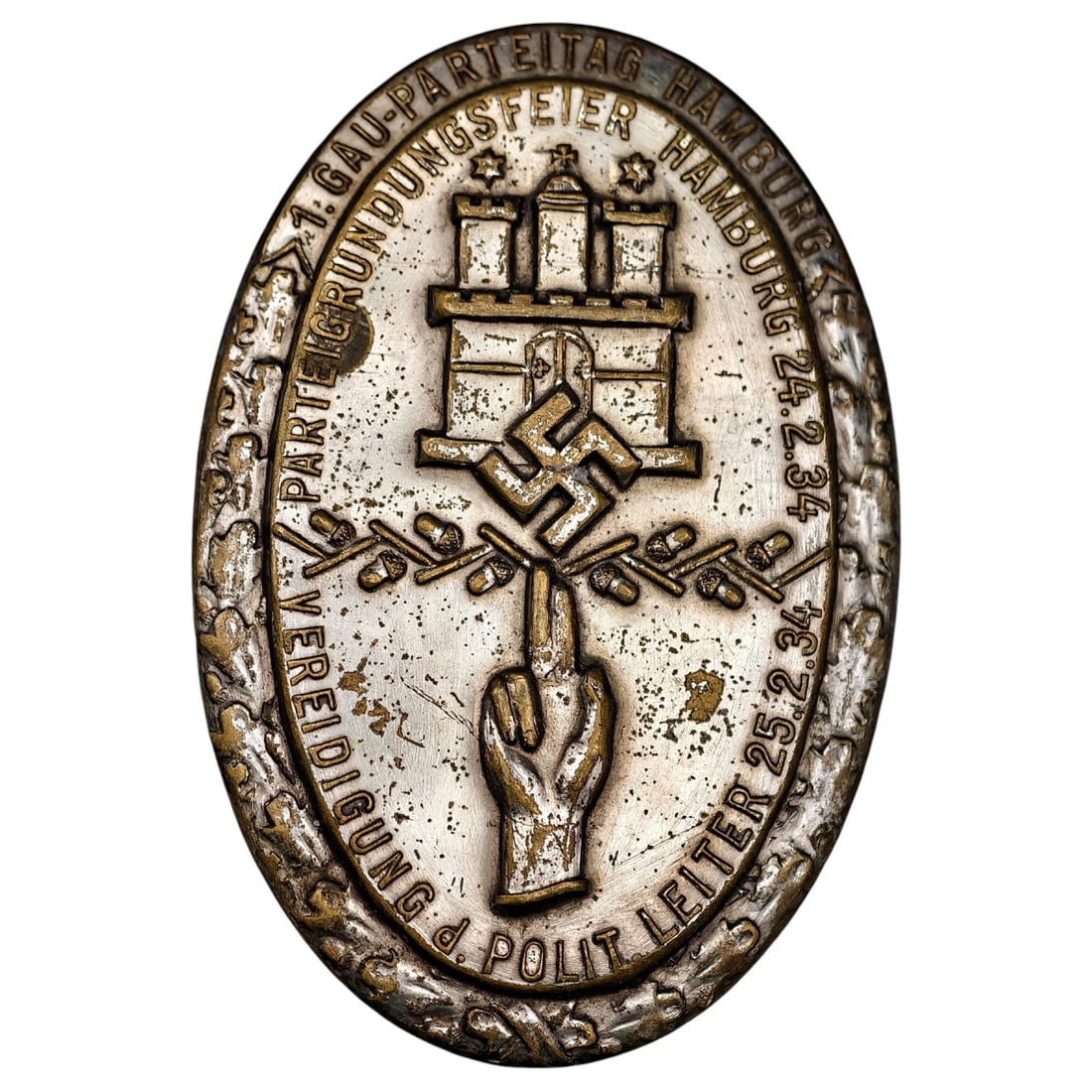 Third Reich Nazi Hamburg 1934 Tinnie Badge: An oval-shaped commemorative tinnie/badge issued for the '1. Gau-Parteitag Hamburg' and 'Parteigrundungsfeier Hamburg' event dated 24.2.34, with 'Vereidigung d. Polit Leiter 25.2.34' also inscribed. T