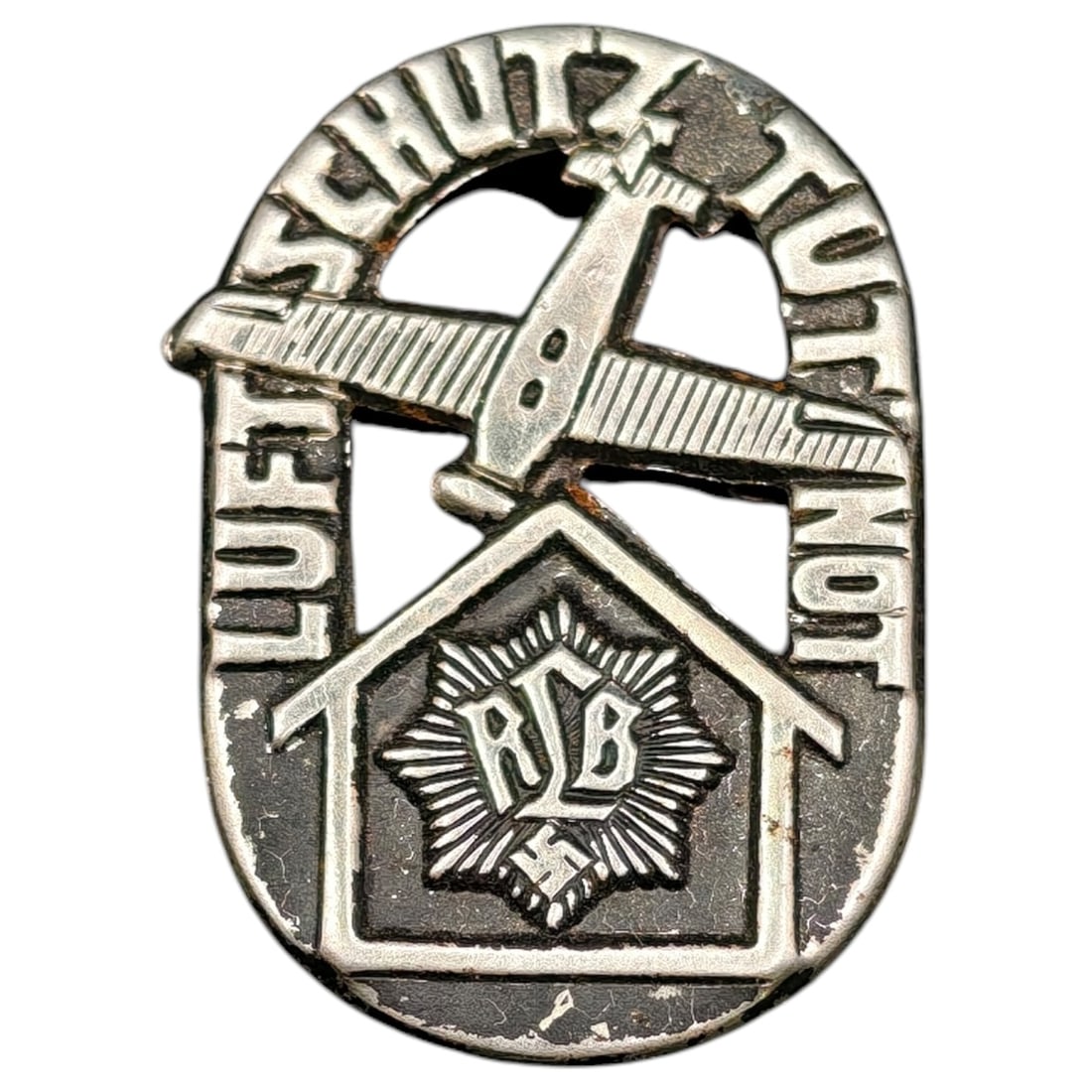 Third Reich Luftschutz RLB Tinnie Badge: A pressed metal membership badge/tinnie for the Reichsluftschutzbund (RLB), inscribed "LUFTSCHUTZ TUT NOT" ("Air protection is necessary") around an aircraft motif above a house pediment enclosing the